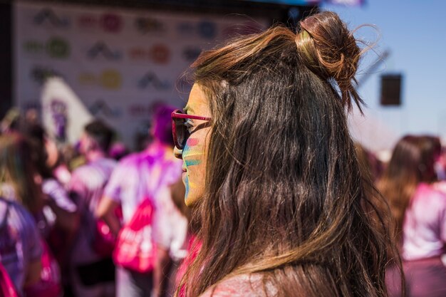 Junge Frau mit gemalter holi Farbe auf ihrem Gesicht, das weg schaut