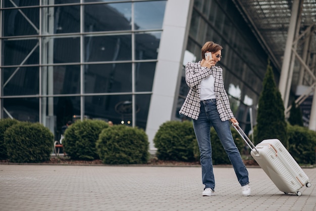 Junge Frau mit Gepäck am Flughafen reisen und telefonieren