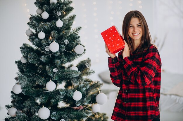 Junge Frau mit Geschenkbox durch den Weihnachtsbaum