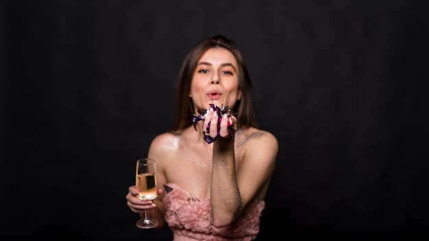Junge Frau mit Glas Getränk und Anlagen in der Hand, die Kuss senden