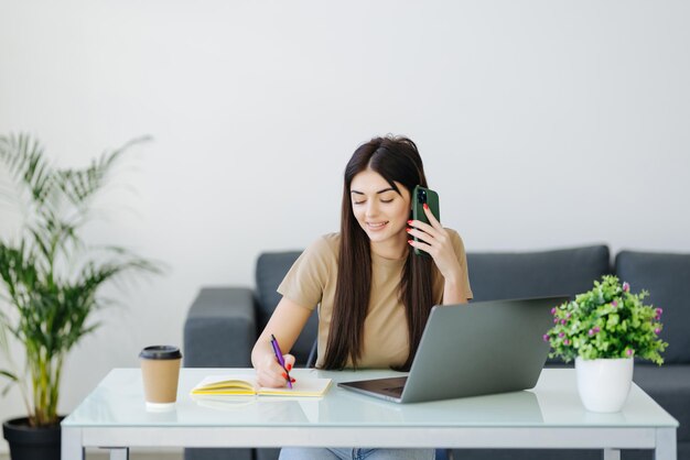 Junge Frau mit Handy und Laptop zu Hause