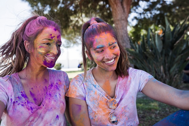 Junge Frau mit ihrem Freund bedeckt im holi Pulver, das selfie auf Mobile nimmt