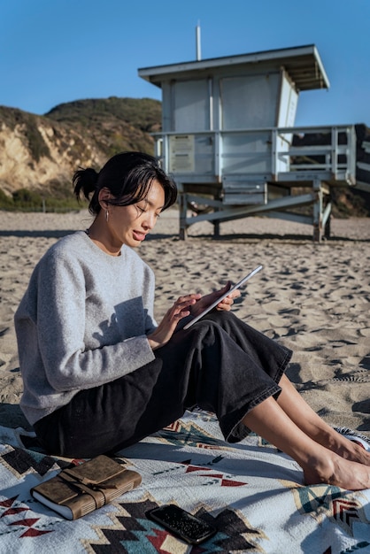 Kostenloses Foto junge frau mit ihrem tablet am strand