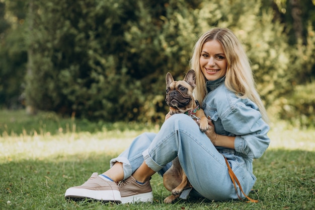 Junge Frau mit ihrer französischen Bulldogge des Haustieres im Park