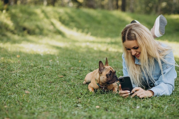 Junge Frau mit ihrer französischen Bulldogge des Haustieres im Park