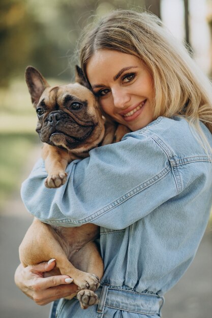 Junge Frau mit ihrer französischen Bulldogge des Haustieres im Park