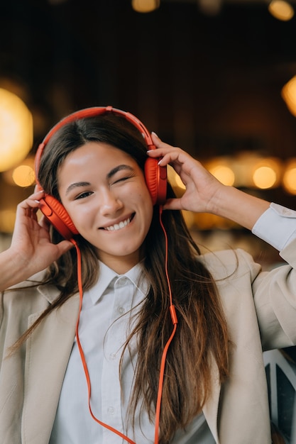 Junge Frau mit Kopfhörern hört Musik, während sie in Cafés sitzt