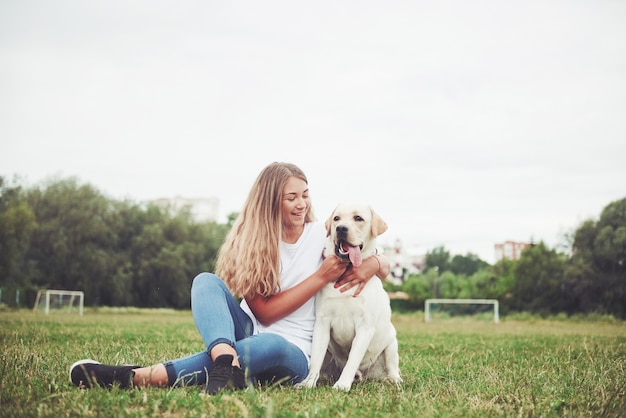 junge Frau mit Labrador im Freien. Frau auf einem grünen Gras mit Hund Labrador Retriever.