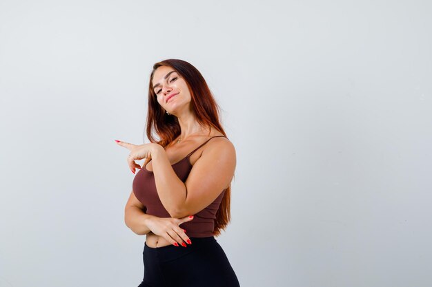 Junge Frau mit langen Haaren in einem braunen bauchfreien Top