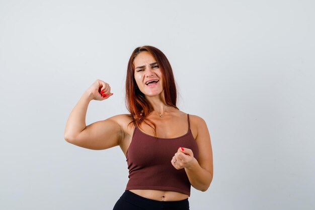 Junge Frau mit langen Haaren in einem braunen bauchfreien Top