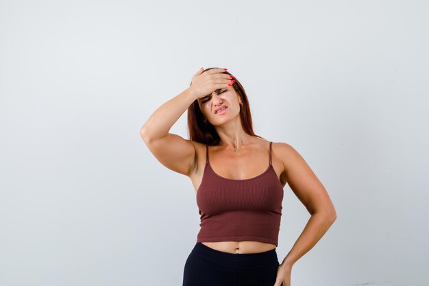 Junge Frau mit langen Haaren in einem braunen bauchfreien Top