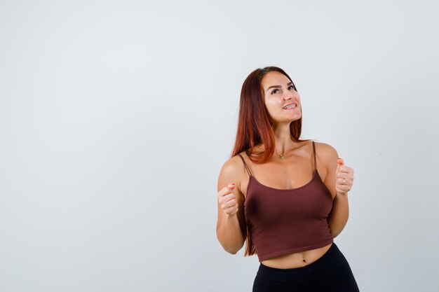 Junge Frau mit langen Haaren in einem braunen bauchfreien Top