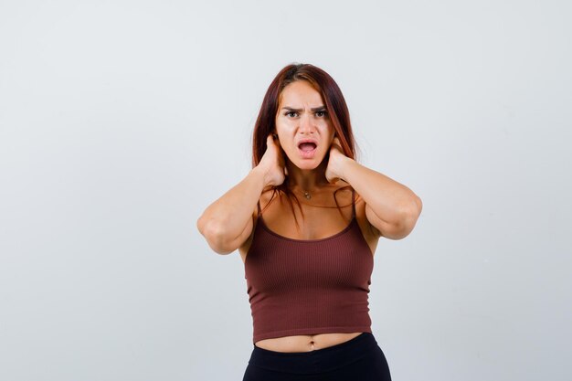 Junge Frau mit langen Haaren in einem braunen bauchfreien Top