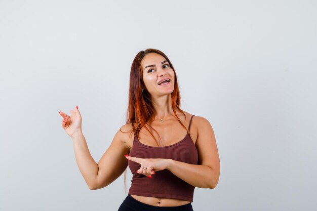 Junge Frau mit langen Haaren in einem braunen bauchfreien Top