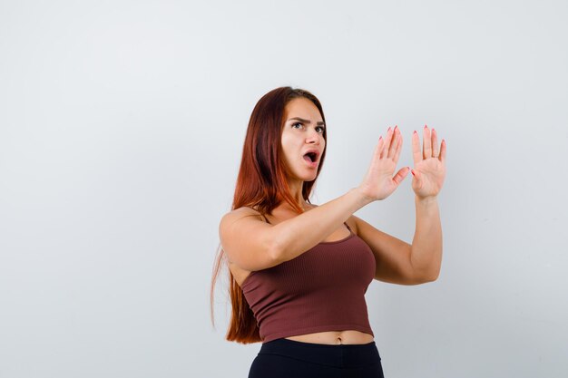 Junge Frau mit langen Haaren in einem braunen bauchfreien Top