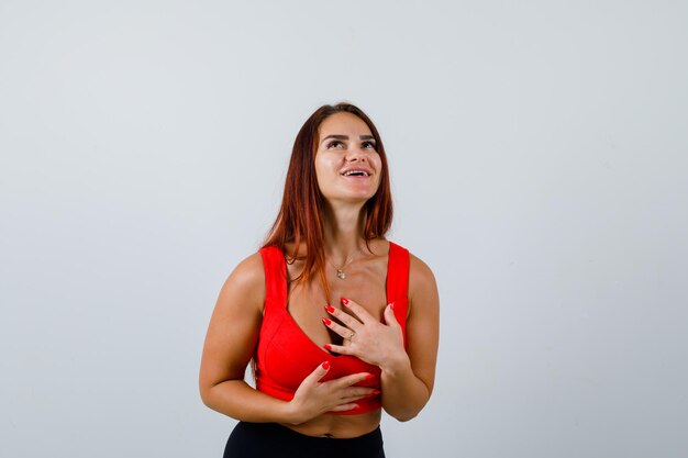 Junge Frau mit langen Haaren in einem orangefarbenen Trägershirt