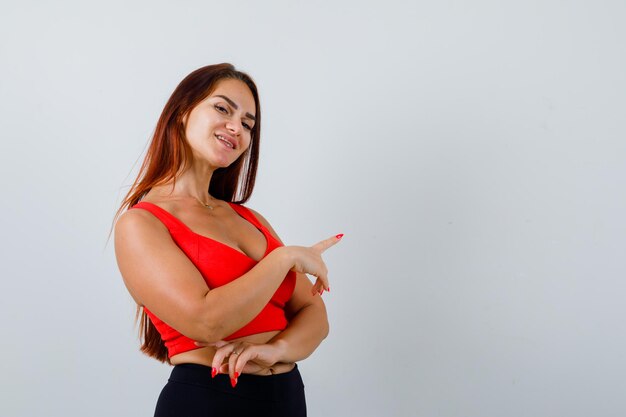 Junge Frau mit langen Haaren in einem orangefarbenen Trägershirt