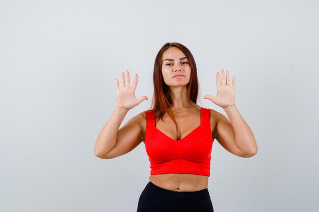 Junge Frau mit langen Haaren in einem orangefarbenen Trägershirt