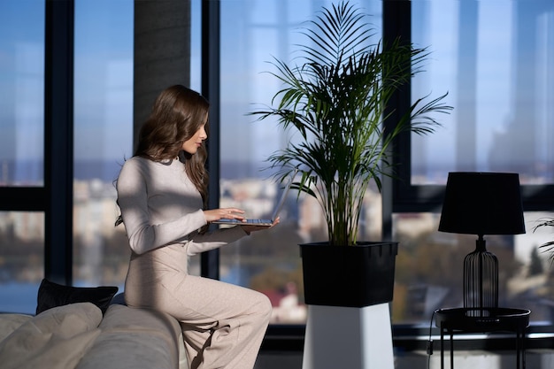 Junge Frau mit Laptop beim Sitzen auf der Couch