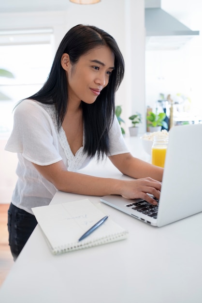 Junge Frau mit Laptop und Notizbuch mit Stift für Notizen