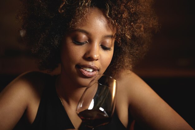 Junge Frau mit lockigem Haar und einem Glas Rotwein