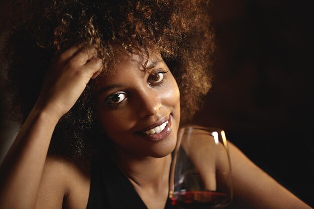 Junge Frau mit lockigem Haar und einem Glas Rotwein