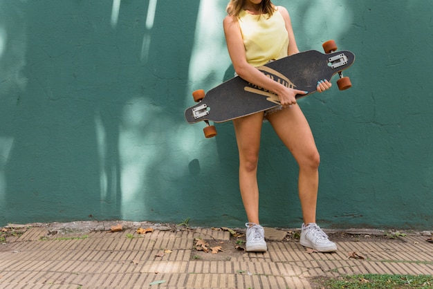 Junge Frau mit Longboard auf grünem Hintergrund