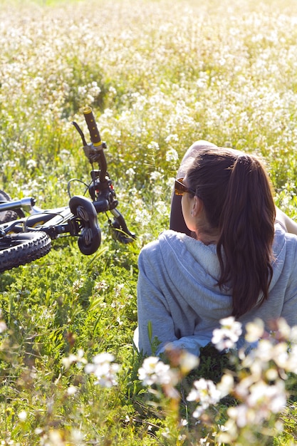 Junge Frau mit Mountainbike auf dem Feld gestreckt