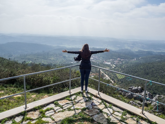 Junge Frau mit offenen Armen, die den schönen Blick auf die Berge genießen