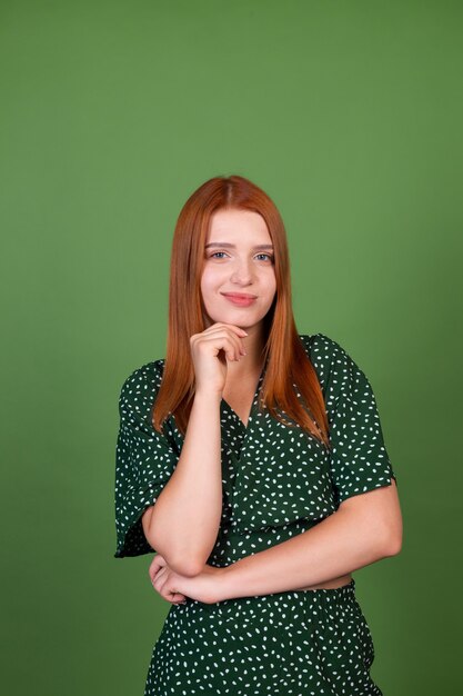 Junge Frau mit rotem Haar auf grüner Wand nachdenkliches Fragen