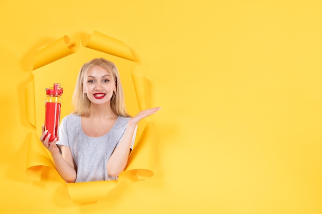 Junge Frau mit roter Flasche auf gelbem Hintergrund Gesichtsfit Sport Athlet Gym