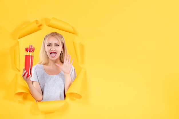 Junge Frau mit roter Flasche auf gelber Fläche