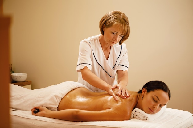Junge Frau mit Rückenmassage durch weibliche Therapeutin im Spa Schwerpunkt liegt auf Massagetherapeutin