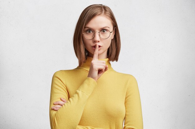 Junge Frau mit runder Brille und gelbem Pullover