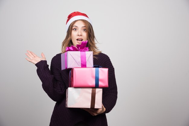 Junge Frau mit Sankt-Hut, der Geschenkboxen hält, präsentiert.