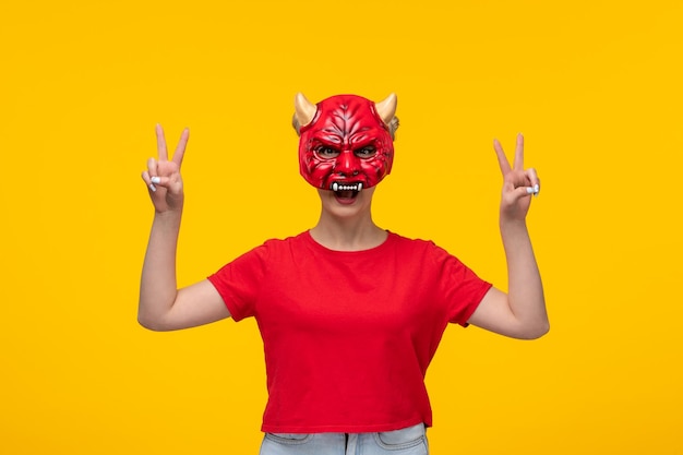 Junge Frau mit schrecklicher Teufelsmaske auf gelbem Hintergrund Halloween-Cartoon