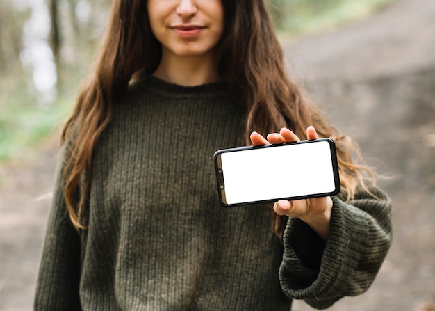 Kostenloses Foto junge frau mit smartphoneschablone in der natur