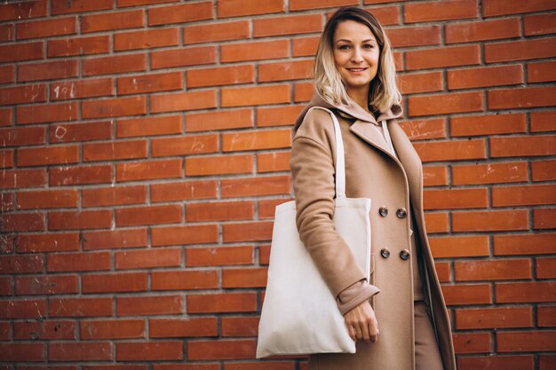 Junge Frau mit Tasche durch die Backsteinmauer