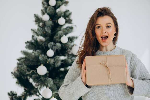 Junge Frau mit Weihnachtsgeschenken durch den Weihnachtsbaum