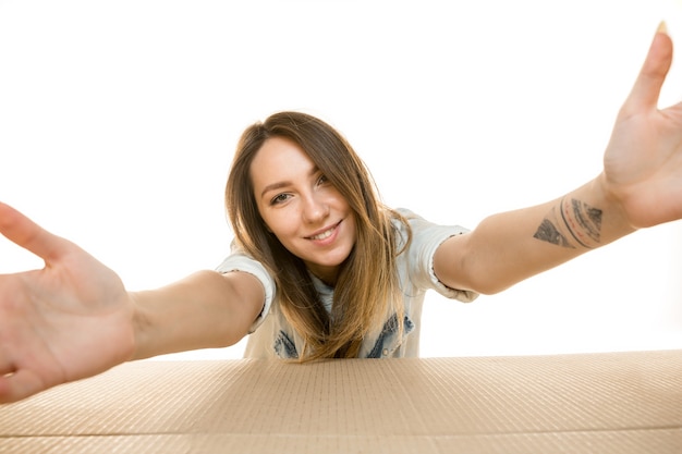 Junge frau öffnet das größte postpaket isoliert auf weiß