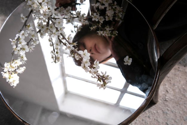 Kostenloses Foto junge frau posiert mit spiegel auf stuhl und blume