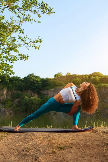 Junge Frau praktiziert Yoga in der Nähe des Flusses