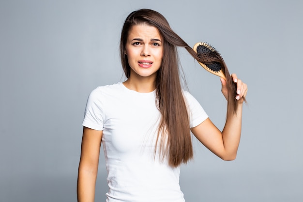 Junge Frau Probleme mit Haaren, gespaltenes schwaches Haar, verwirrtes Haar isoliert auf grau