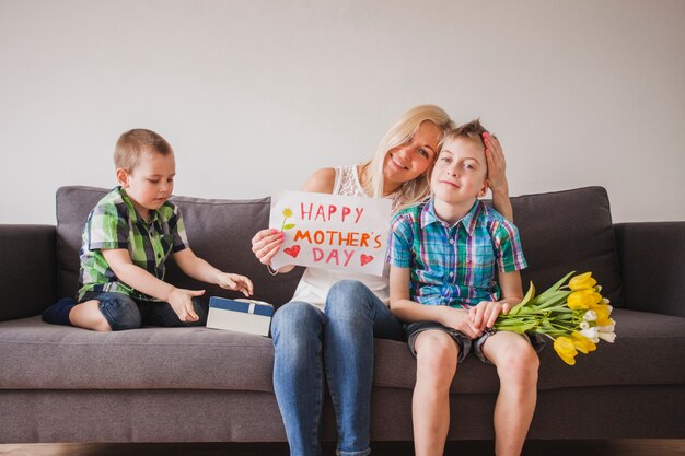 Junge Frau sitzt auf einer Couch mit ihren Kindern