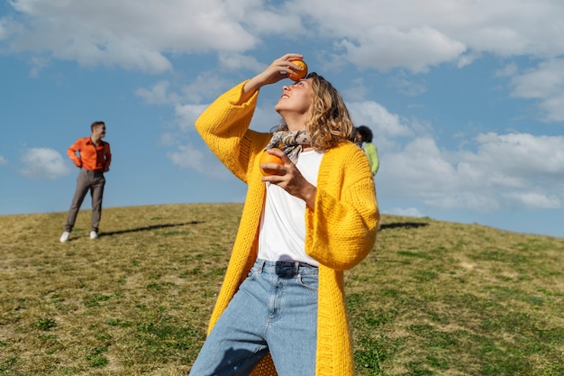 Kostenloses Foto junge frau spielt mit orangen auf einem feld im freien