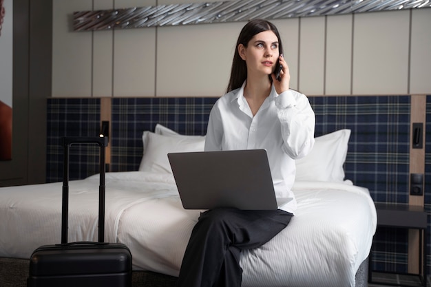 Junge Frau spricht auf ihrem Smartphone in einem Hotelzimmer