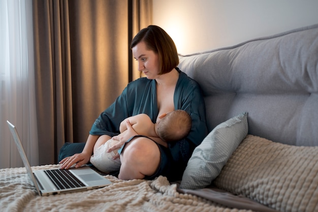 Kostenloses Foto junge frau stillt ihr süßes baby während der arbeit