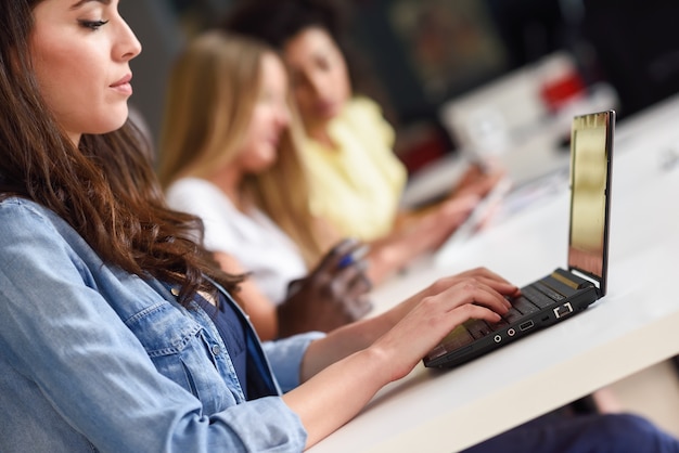 Junge frau studiert mit laptop-computer auf weißem schreibtisch.