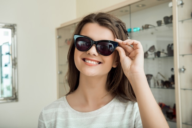 Junge Frau sucht neue Sonnenbrille, um ihren Stil Indoor zu betonen