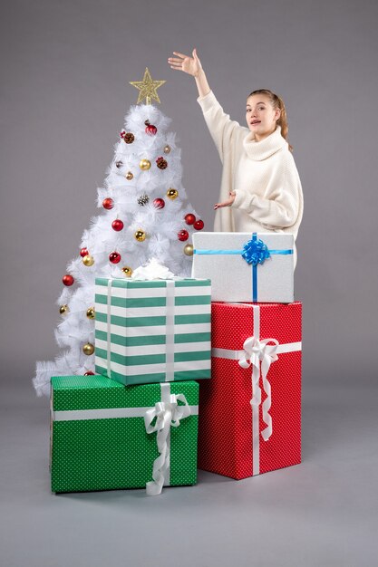 junge Frau um Weihnachtsgeschenke auf grau